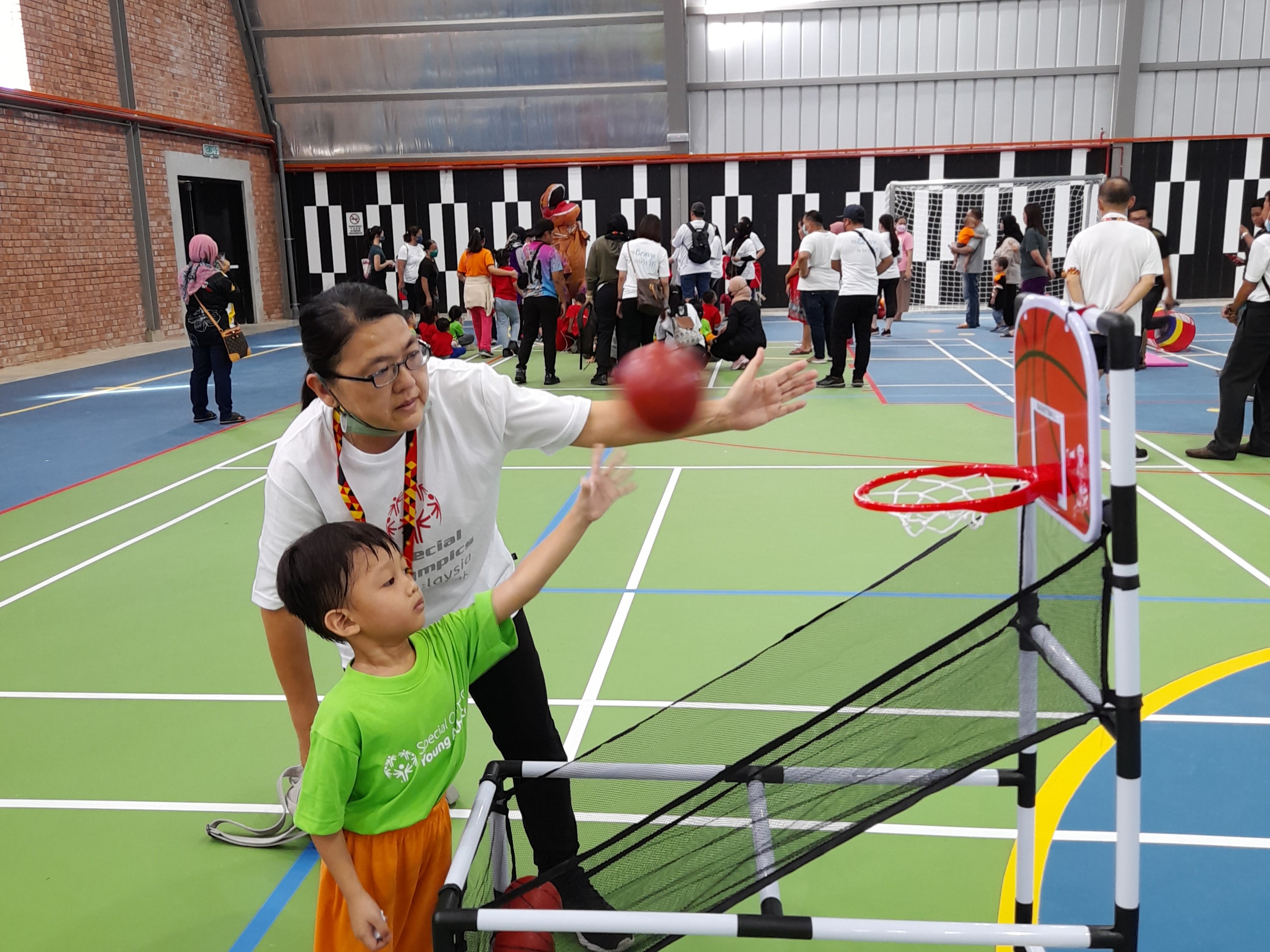 Coach working with Special Olympics athlete on basketball skills in a gym